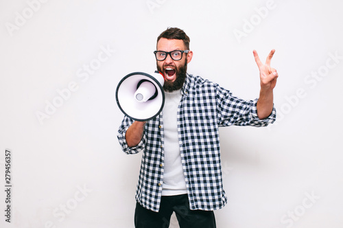 Fashion portrait of emotional hipster man with megaphone on white background in stylish sunglasses. Sales man using megaphone yelling