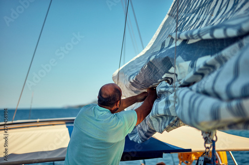 Sailor packing / unpacking main sail wing on the boat. photo