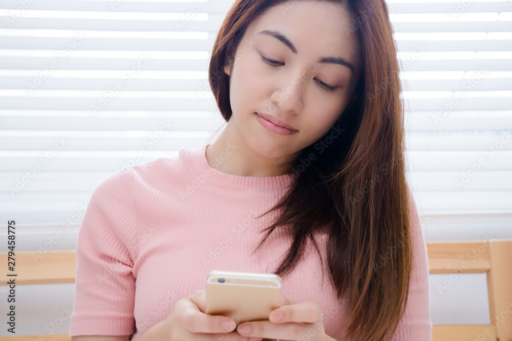 Young Asian woman using a smart phone on a bed. Young Asian woman using a smart phone on a bed.