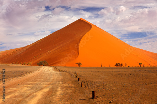 Namibia landscape. Big orange dune with blue sky and clouds, Sossusvlei, Namib desert, Namibia, Southern Africa. Red sand, biggest dune in the world. Travelling in Africa.