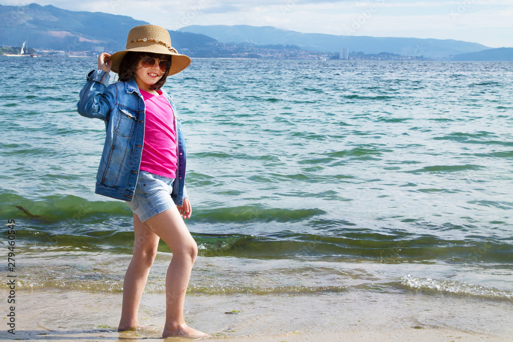 girl in hat and sunglasses walking on the beach, concept of summer holidays and relaxation
