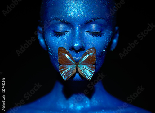 Fashion model woman in blue bright sparkles and neon lights posing in studio.  Portrait of beautiful sexy woman with blue butterfly. Art design colorful glitter glowing make up photo