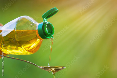 Hand pouring Vegetable oil from bottle to spoon