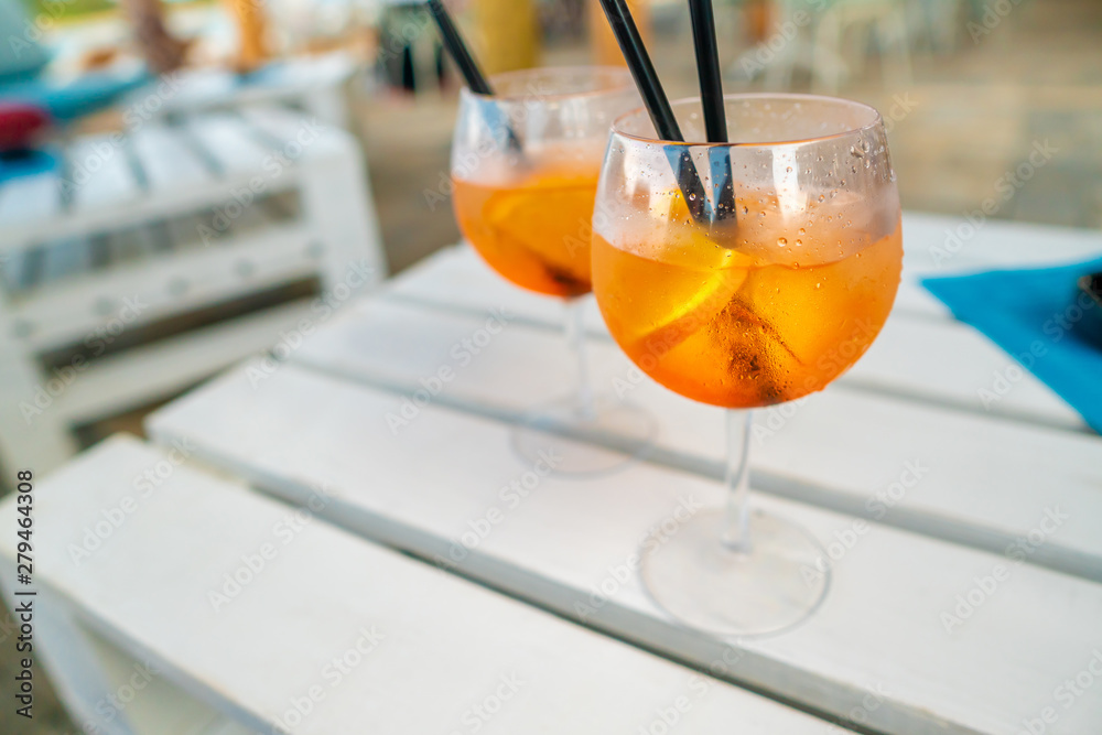 Delicious classic iced aperol spritz cocktail with ice cubes on a hot tropical beach in summer sunshine Delicious classic iced aperol spritz cocktail with ice cubes on a hot tropical beach in summer sunshine
