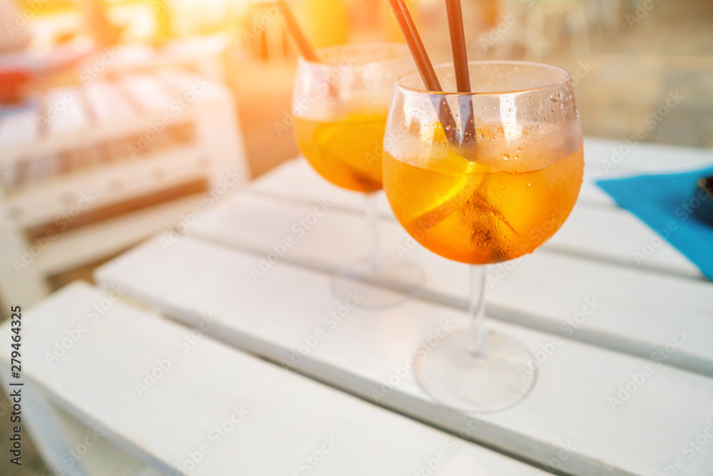 Delicious classic iced aperol spritz cocktail with ice cubes on a hot tropical beach in summer sunshine Delicious classic iced aperol spritz cocktail with ice cubes on a hot tropical beach in summer sunshine