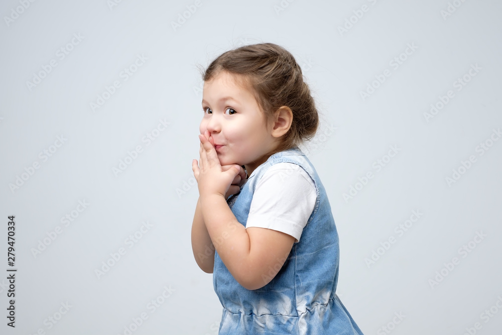 Surprised little girl covered mouth with her hands waiting for gift on her birthday being curious. Surprised little girl covered mouth with her hands waiting for gift on her birthday being curious.