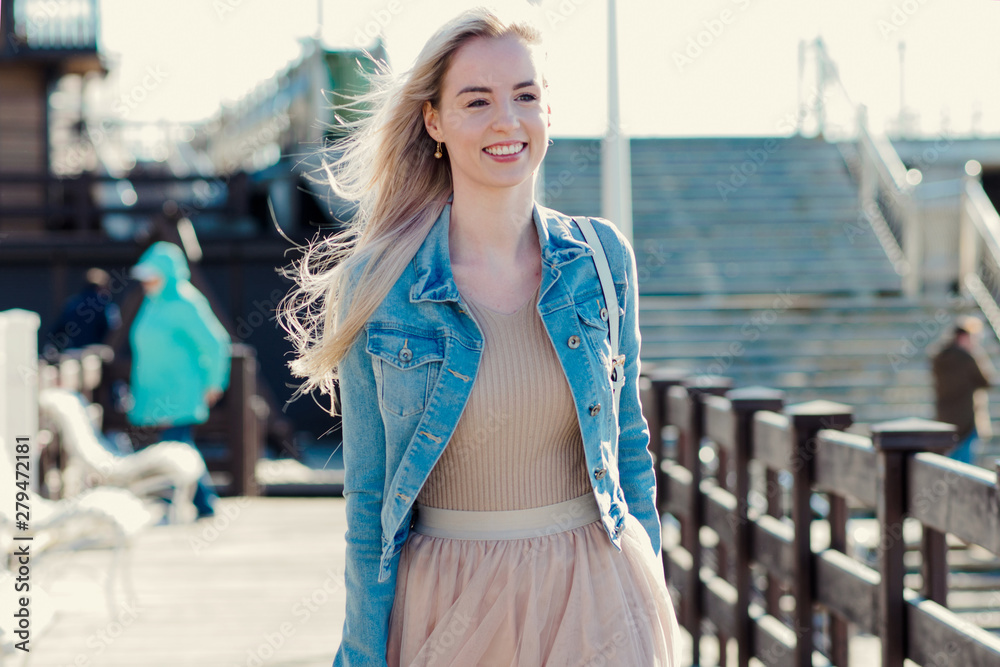 Young cheerful girl on the seashore. Young blonde woman smiling.