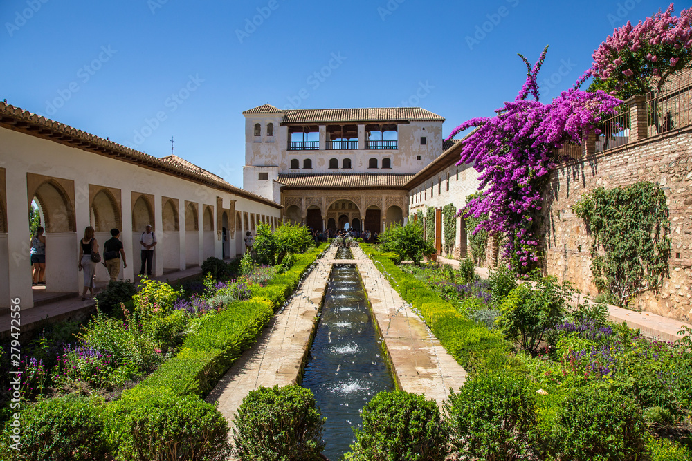 Granada, Andalucia / Spain »; July 2018: Water jets in the gardens of Generalife Alhambra with the building in the background