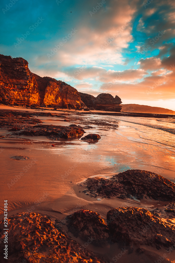 Waves washing over rocks at beach with cliffs in background