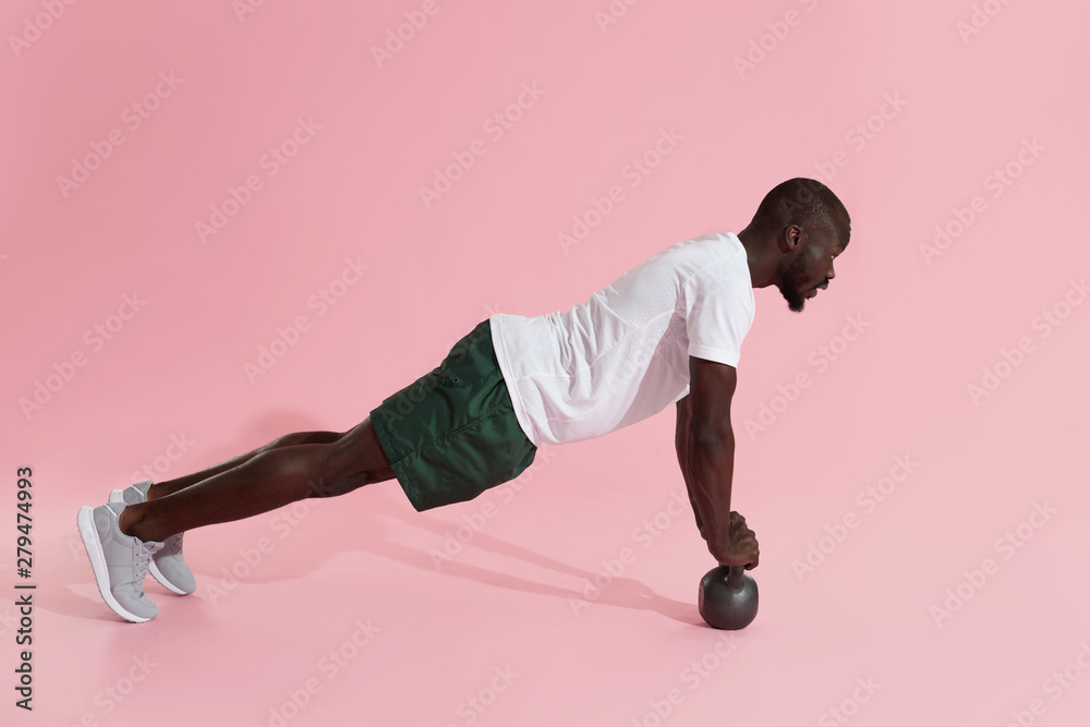 Naklejka premium Sports man exercising, doing kettlebell push-up workout