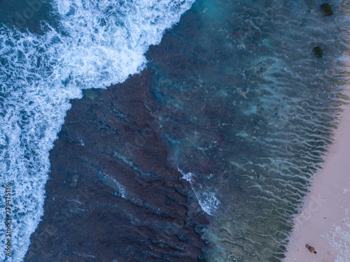 Above the ocean, aerial view at the waves and surface near coast line
