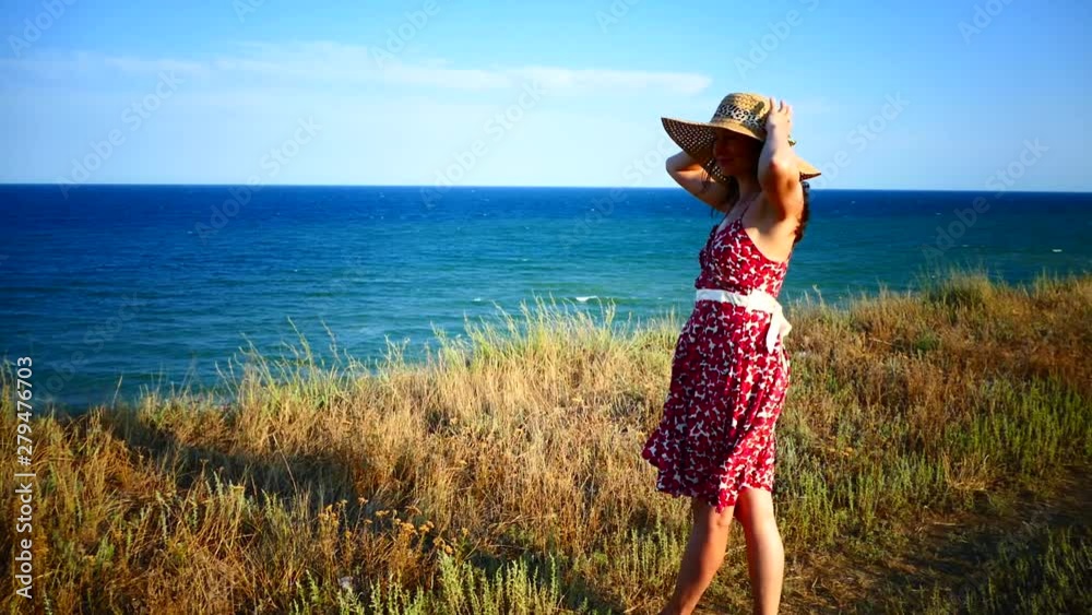 The girl looks at the beautiful landscape in the morning. Stand over a cliff by the sea. Happy girl in a hat on vacation. The girl looks at the beautiful landscape in the morning. Stand over a cliff by the sea. Happy girl in a hat on vacation.