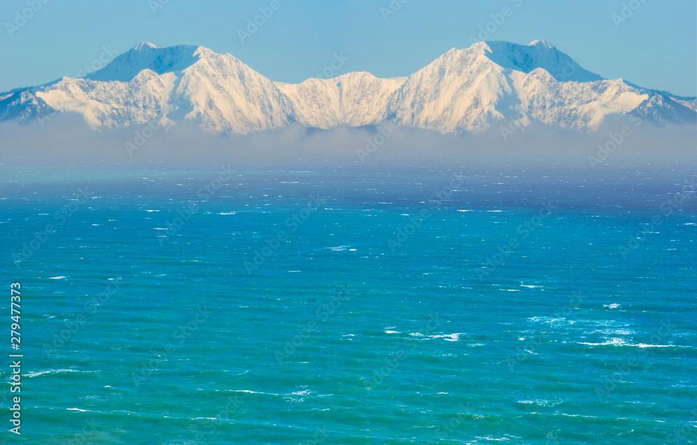 high mountain chain in a snow in a mist beyond emerald sea high mountain chain in a snow in a mist beyond emerald sea