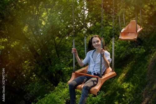 Happy child teenage girl riding chain carousel swing at amusement park 
