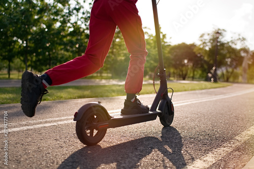 Close up of teen riding electric kick scooter in the park at sunset          photo