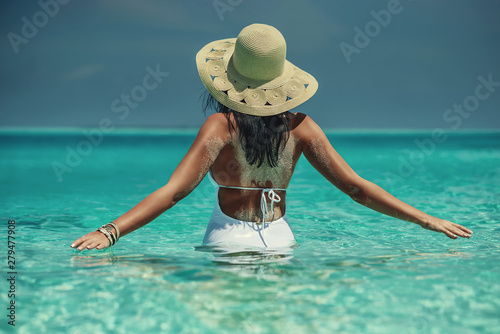 Young sexy woman on white sand beach with turquoise sea, luxury resort in the Maldives