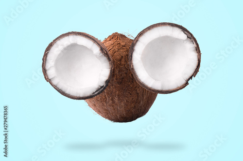 Halves and whole tropical nut with palm leaf in the form of a face on a blue background, coconut muzzle