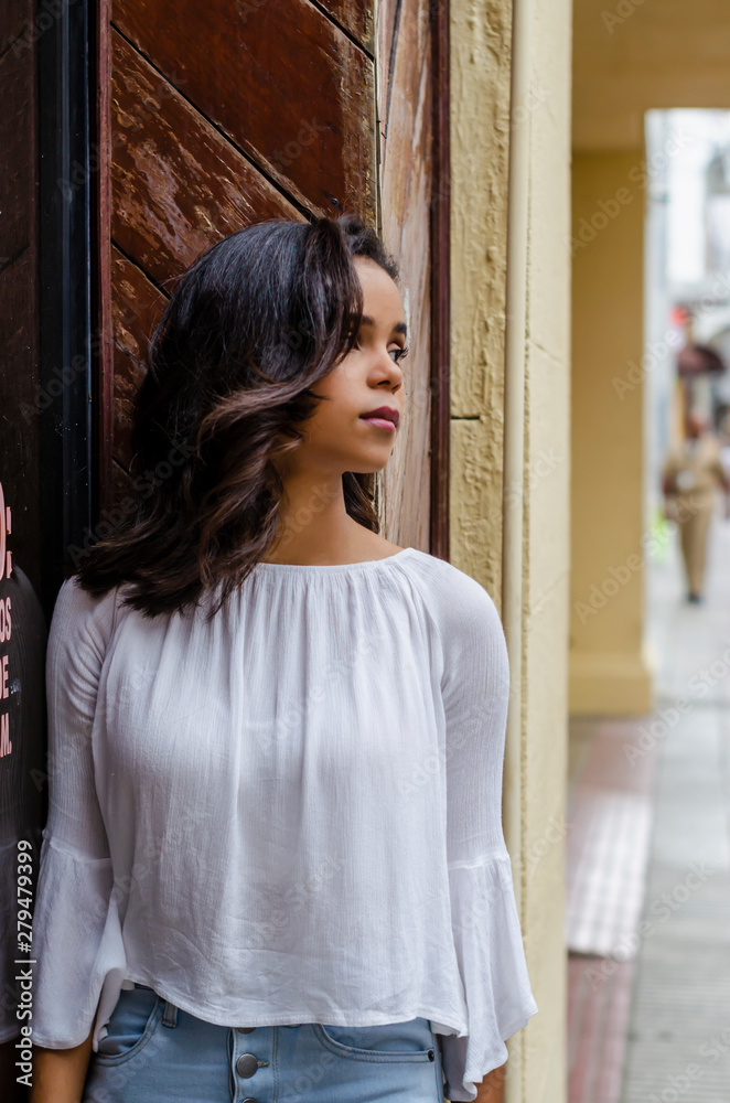 Outdoor portrait of young beautiful girl 9 to 25 years old posing in street. wearing white blouse and tight jeans and sapatillas. City lifestyle. Female fashion concept. Outdoor portrait of young beautiful girl 9 to 25 years old posing in street. wearing white blouse and tight jeans and sapatillas. City lifestyle. Female fashion concept.