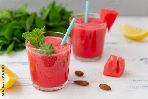 Cold watermelon smoothie with mint and lemon in glasses. A cocktail of watermelon juice, on wooden light blue background.