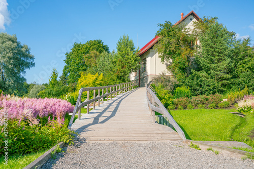 Wooden footbridge to the house among the flowers.