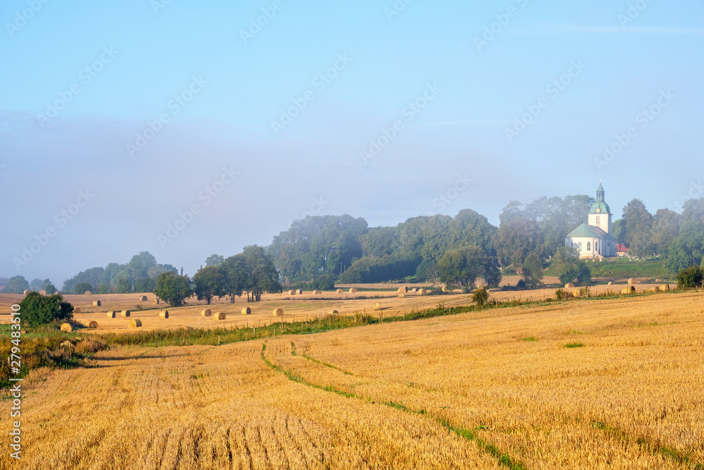 Stubble field with bales and a Country church Stubble field with bales and a Country church