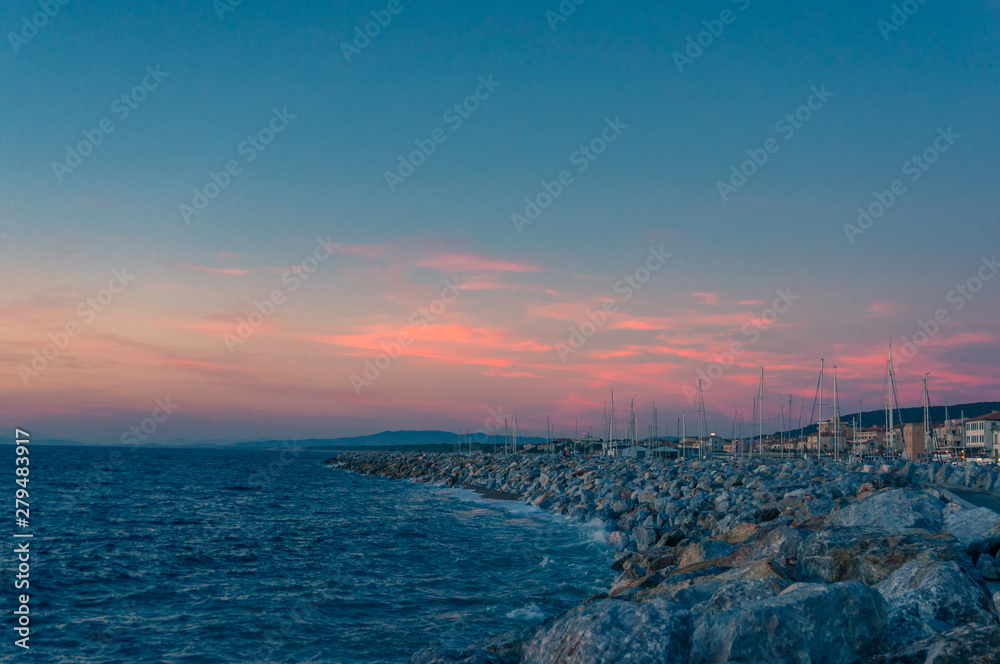 Romantic coastal sunset seascape with blue sky and bright pink clouds