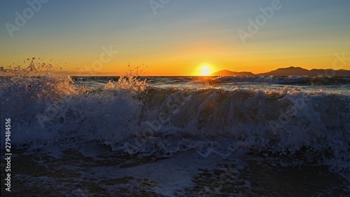 Beautiful sunset with sea and waves. Natural colorful background. Concept for summer and sea vacation. Greece - island of Kos.