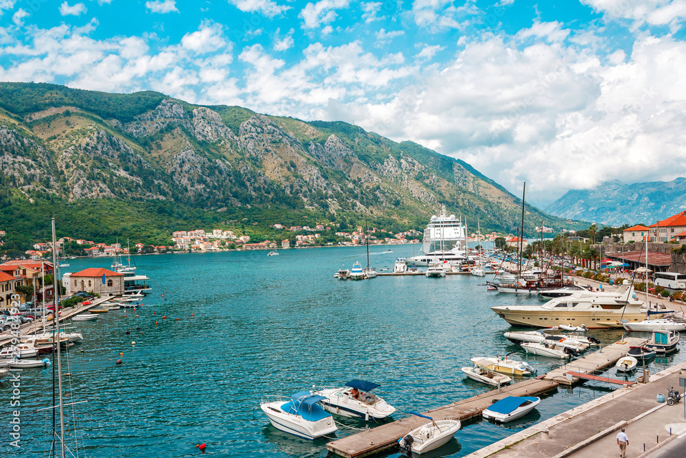 Ancient town Kotor with marina and yachts on the water, old stone houses surrounded by mountains, Montenegro