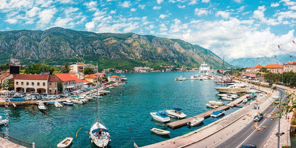 Ancient town Kotor with marina and yachts on the water, old stone houses surrounded by mountains, Montenegro. Panoramic view