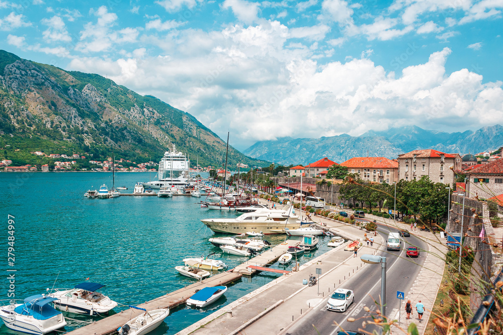 Ancient town Kotor with marina and yachts on the water, old stone houses surrounded by mountains, Montenegro