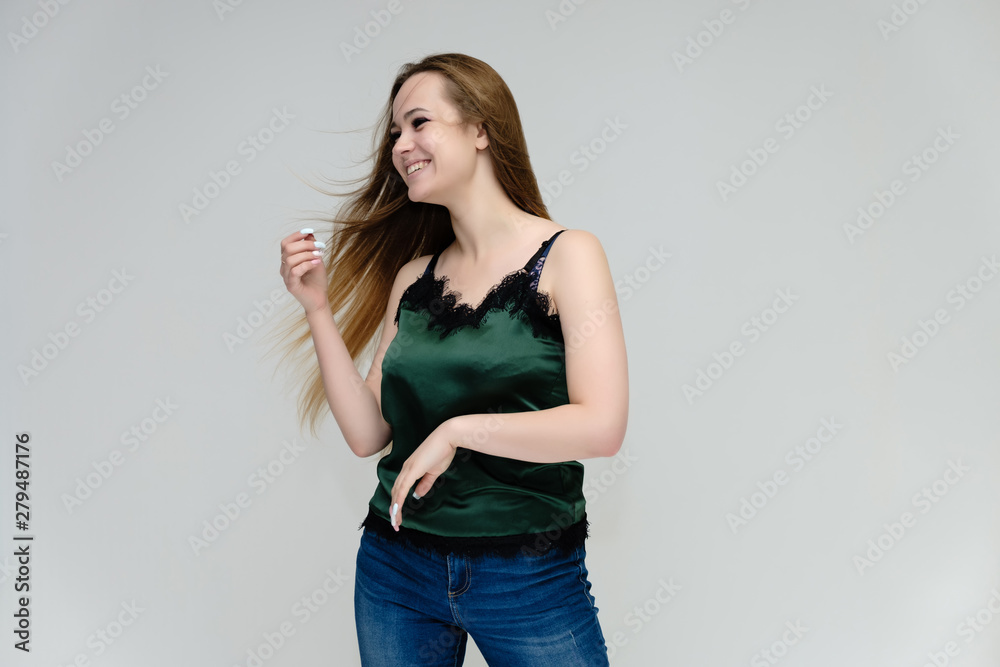 Concept portrait above the knee of a pretty girl, young woman with long beautiful brown hair in a green T-shirt and blue jeans on a white background. In the studio in different poses showing emotions. Concept portrait above the knee of a pretty girl, young woman with long beautiful brown hair in a green T-shirt and blue jeans on a white background. In the studio in different poses showing emotions.