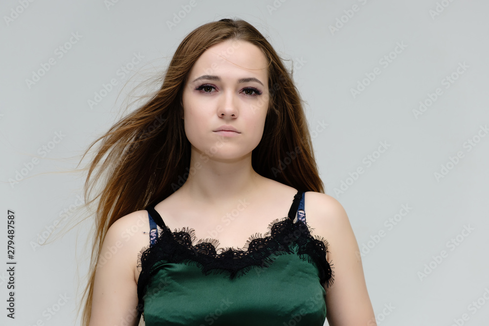 Concept close-up portrait of a pretty girl, young woman with long beautiful brown hair in a green t-shirt on a white background. In the studio in different poses showing emotions. Concept close-up portrait of a pretty girl, young woman with long beautiful brown hair in a green t-shirt on a white background. In the studio in different poses showing emotions.