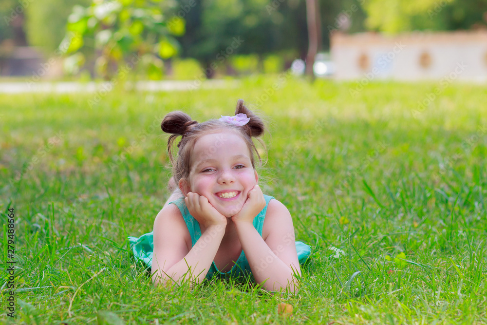 Cute girl lying on the green grass, outdoors, summer time, blurred background Cute girl lying on the green grass, outdoors, summer time, blurred background