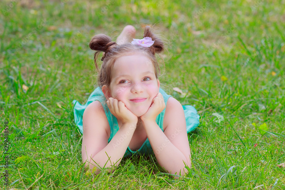 Cute girl lying on the green grass, outdoors, summer time, blurred background Cute girl lying on the green grass, outdoors, summer time, blurred background