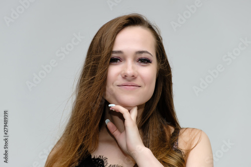 Concept close-up portrait of a pretty girl, young woman with long beautiful brown hair and beautiful face skin on a white background. In the studio in different poses showing emotions.