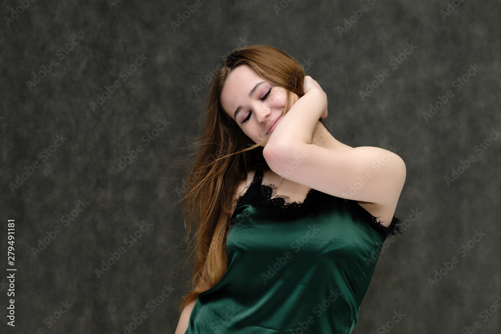 Concept portrait of the waist of a pretty girl, a young woman with long beautiful brown hair and a green T-shirt on a gray background. In the studio in different poses showing emotions. Concept portrait of the waist of a pretty girl, a young woman with long beautiful brown hair and a green T-shirt on a gray background. In the studio in different poses showing emotions.