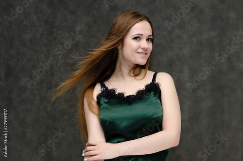 Concept portrait of the waist of a pretty girl, a young woman with long beautiful brown hair and a green T-shirt on a gray background. In the studio in different poses showing emotions. © Вячеслав Чичаев