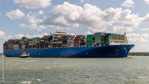 grosses Containerschiff beim einlaufen in den Hafen, in begleitung von schleppschiffen