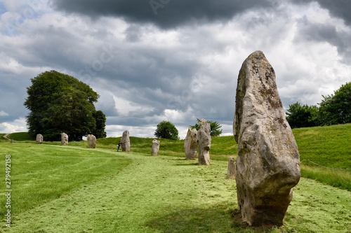 Visitor touching a Neolithic standing monolith at Avebury Henge England south west sector edge of the largest megalithic stone circle in the world photo