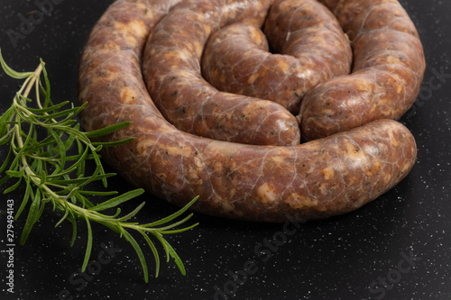 Raw homemade stuffed pork sausages and rosemarin isolated on a blackboard.