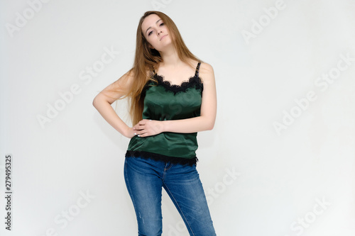 Concept portrait above the knee of a pretty girl, a young woman with long beautiful brown hair and a green t-shirt and blue jeans on a white background. In studio in different poses showing emotions.