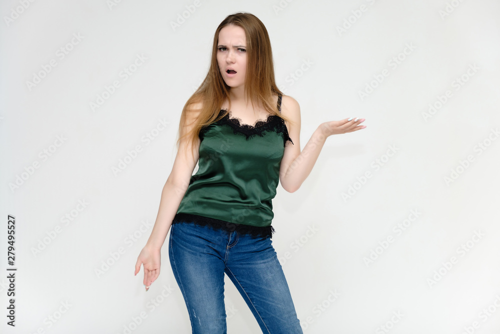 Concept portrait above the knee of a pretty girl, a young woman with long beautiful brown hair and a green t-shirt and blue jeans on a white background. In studio in different poses showing emotions. Concept portrait above the knee of a pretty girl, a young woman with long beautiful brown hair and a green t-shirt and blue jeans on a white background. In studio in different poses showing emotions.