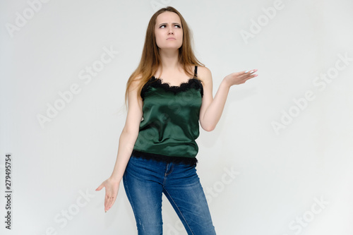 Concept portrait above the knee of a pretty girl, a young woman with long beautiful brown hair and a green t-shirt and blue jeans on a white background. In studio in different poses showing emotions.