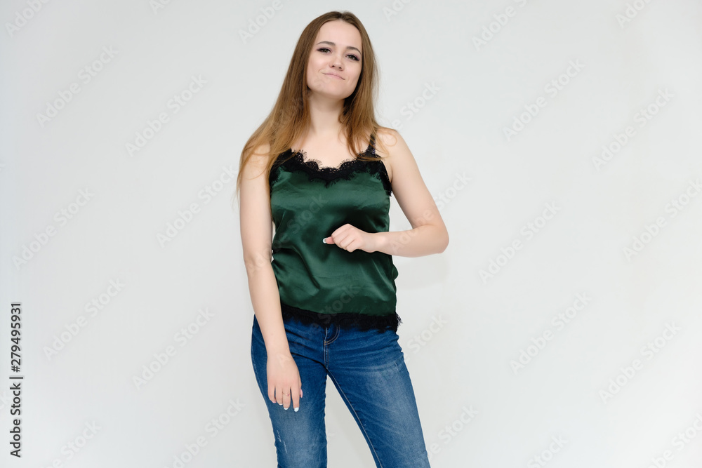 Concept portrait above the knee of a pretty girl, a young woman with long beautiful brown hair and a green t-shirt and blue jeans on a white background. In studio in different poses showing emotions. Concept portrait above the knee of a pretty girl, a young woman with long beautiful brown hair and a green t-shirt and blue jeans on a white background. In studio in different poses showing emotions.