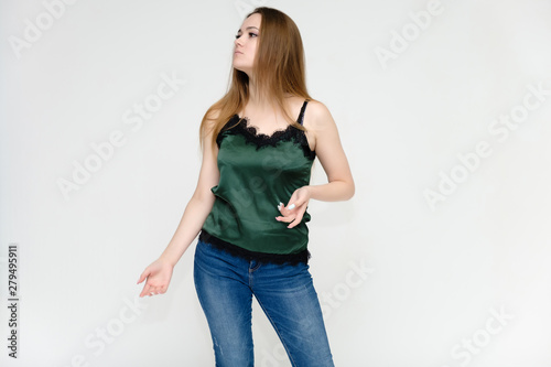 Concept portrait above the knee of a pretty girl, a young woman with long beautiful brown hair and a green t-shirt and blue jeans on a white background. In studio in different poses showing emotions.