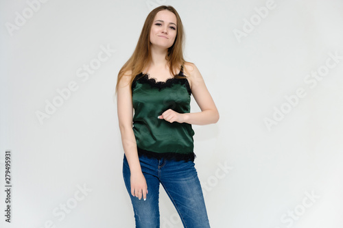 Concept portrait above the knee of a pretty girl, a young woman with long beautiful brown hair and a green t-shirt and blue jeans on a white background. In studio in different poses showing emotions.