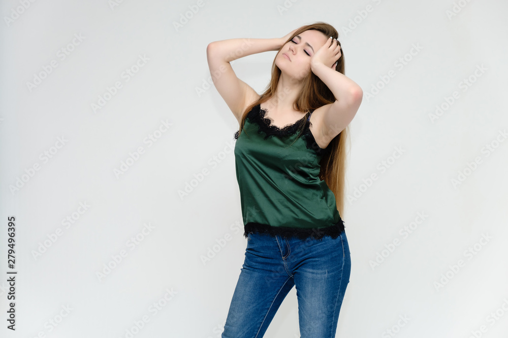 Concept portrait above the knee of a pretty girl, a young woman with long beautiful brown hair and a green t-shirt and blue jeans on a white background. In studio in different poses showing emotions. Concept portrait above the knee of a pretty girl, a young woman with long beautiful brown hair and a green t-shirt and blue jeans on a white background. In studio in different poses showing emotions.