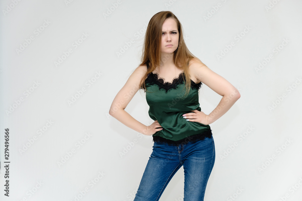 Concept portrait above the knee of a pretty girl, a young woman with long beautiful brown hair and a green t-shirt and blue jeans on a white background. In studio in different poses showing emotions. Concept portrait above the knee of a pretty girl, a young woman with long beautiful brown hair and a green t-shirt and blue jeans on a white background. In studio in different poses showing emotions.