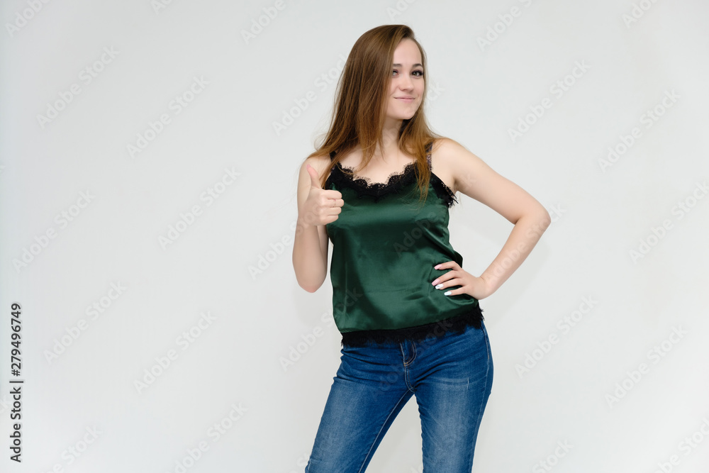 Concept portrait above the knee of a pretty girl, a young woman with long beautiful brown hair and a green t-shirt and blue jeans on a white background. In studio in different poses showing emotions. Concept portrait above the knee of a pretty girl, a young woman with long beautiful brown hair and a green t-shirt and blue jeans on a white background. In studio in different poses showing emotions.