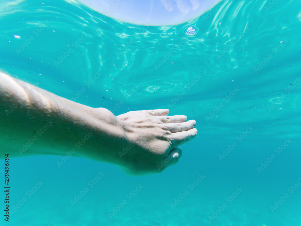 hand underwater swimming in blue water